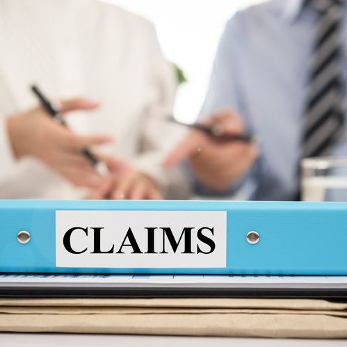 Insurance Claim Documents in Folders With Lawyers in a Meeting