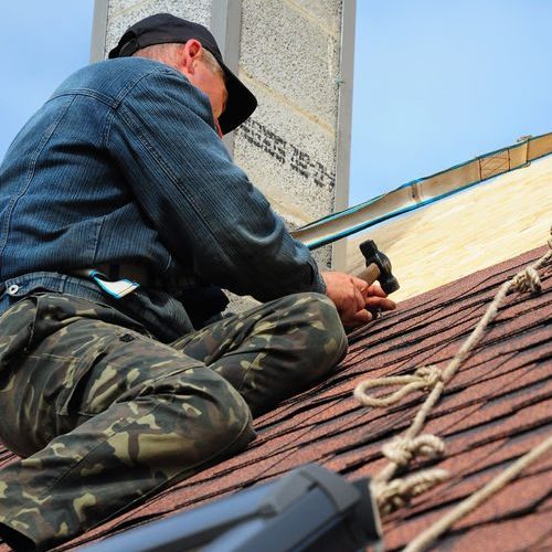 Worker on Roof Hammering Materials