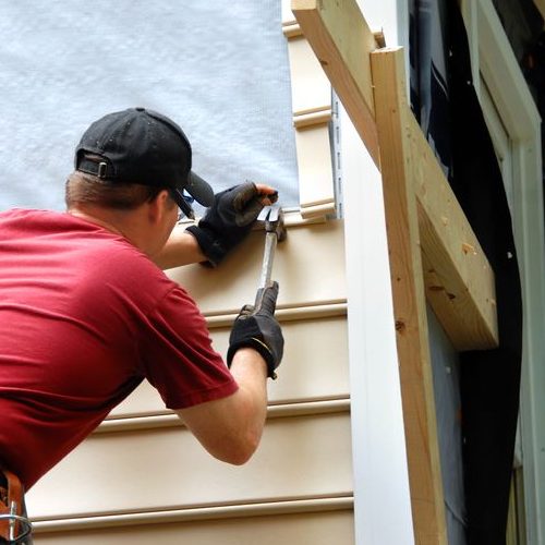 Worker Installing Siding With Hammer & Nails